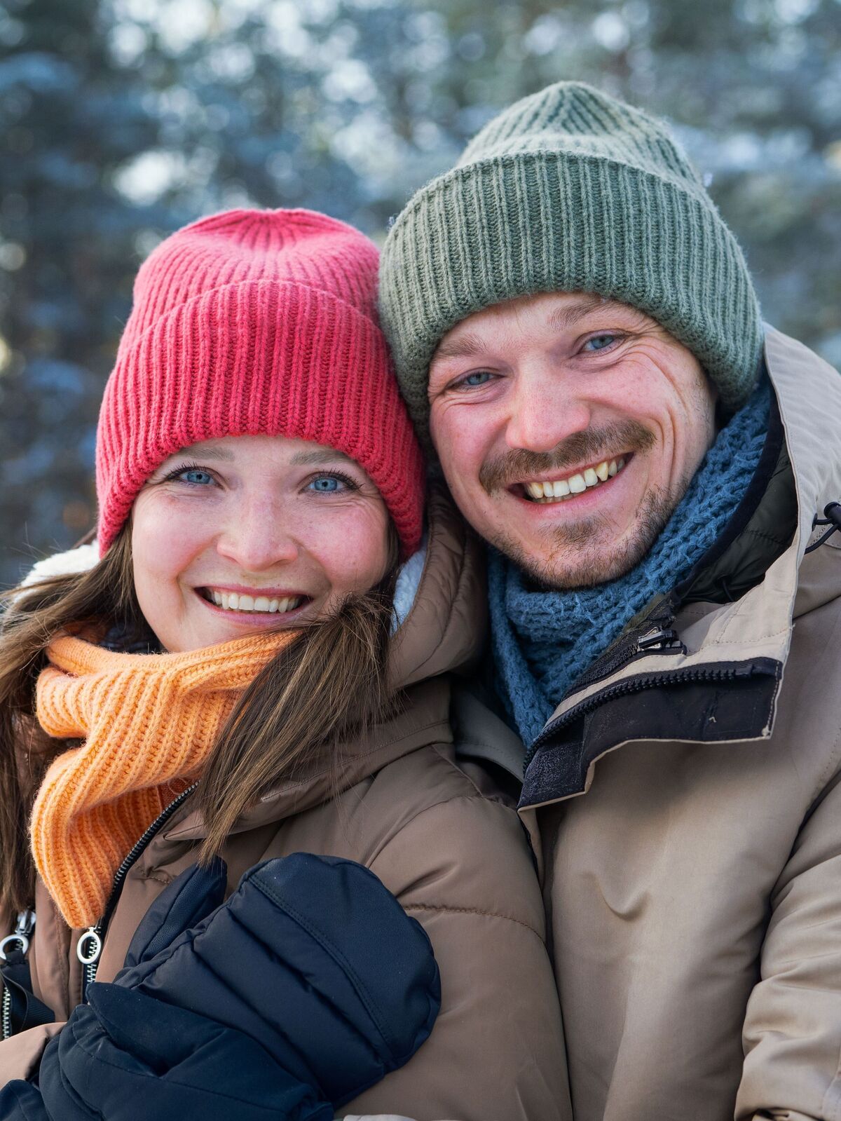 Un couple heureux avec des bonnets colorés dans un environnement hivernal.