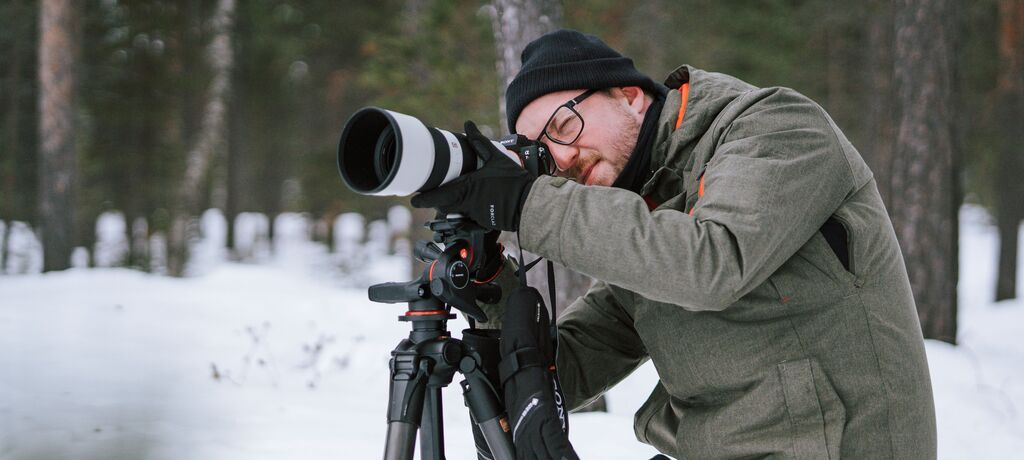Un photographe utilise son objectif zoom pour capturer un paysage d'hiver.