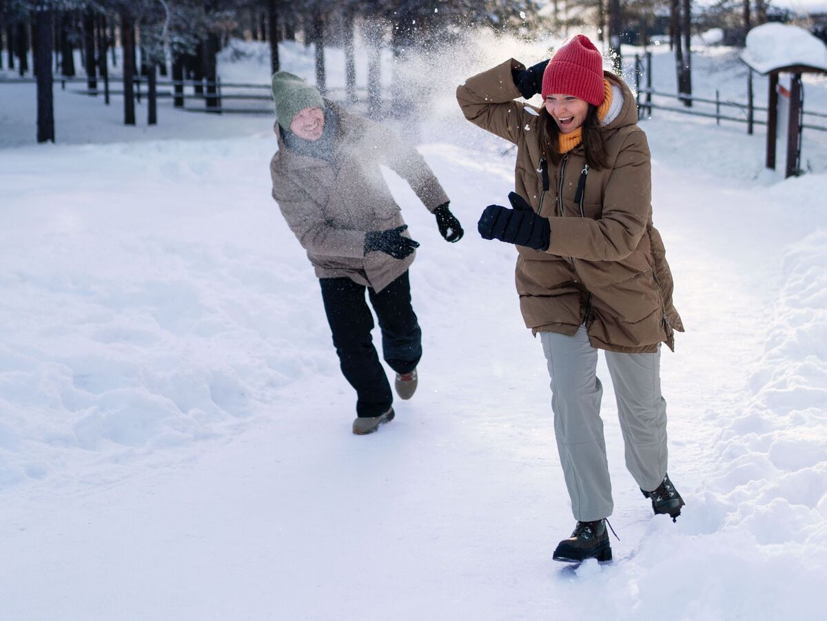 Deux personnes jouent dans la neige et s'amusent.